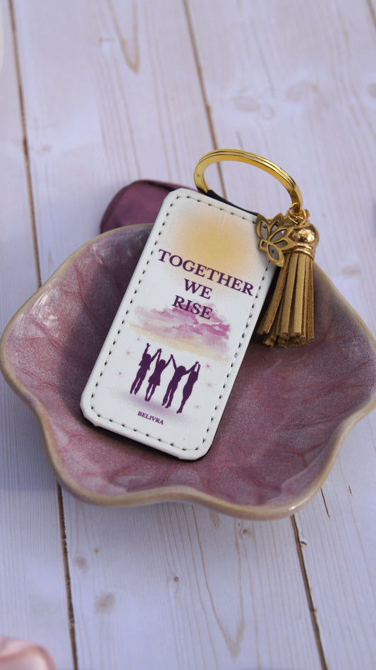PU leather keychain with “Together We Rise” quote, gold lotus charm, and tassel, symbolizing sisterhood and empowerment by Belivra.