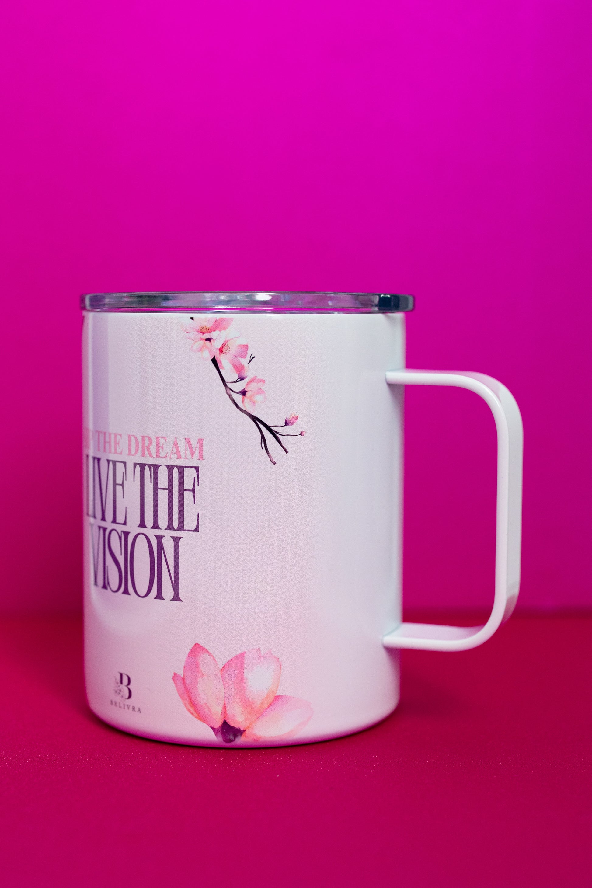 Side view of Belivra ceramic mug with the phrase "Sip the Dream, Live the Vision" in purple and pink text, complemented by soft cherry blossom details. The mug is displayed with a spill-resistant lid, making it perfect for enjoying coffee, tea, or other beverages while staying inspired throughout the day. Ideal for empowering moments, positive affirmations, and mindful sipping.