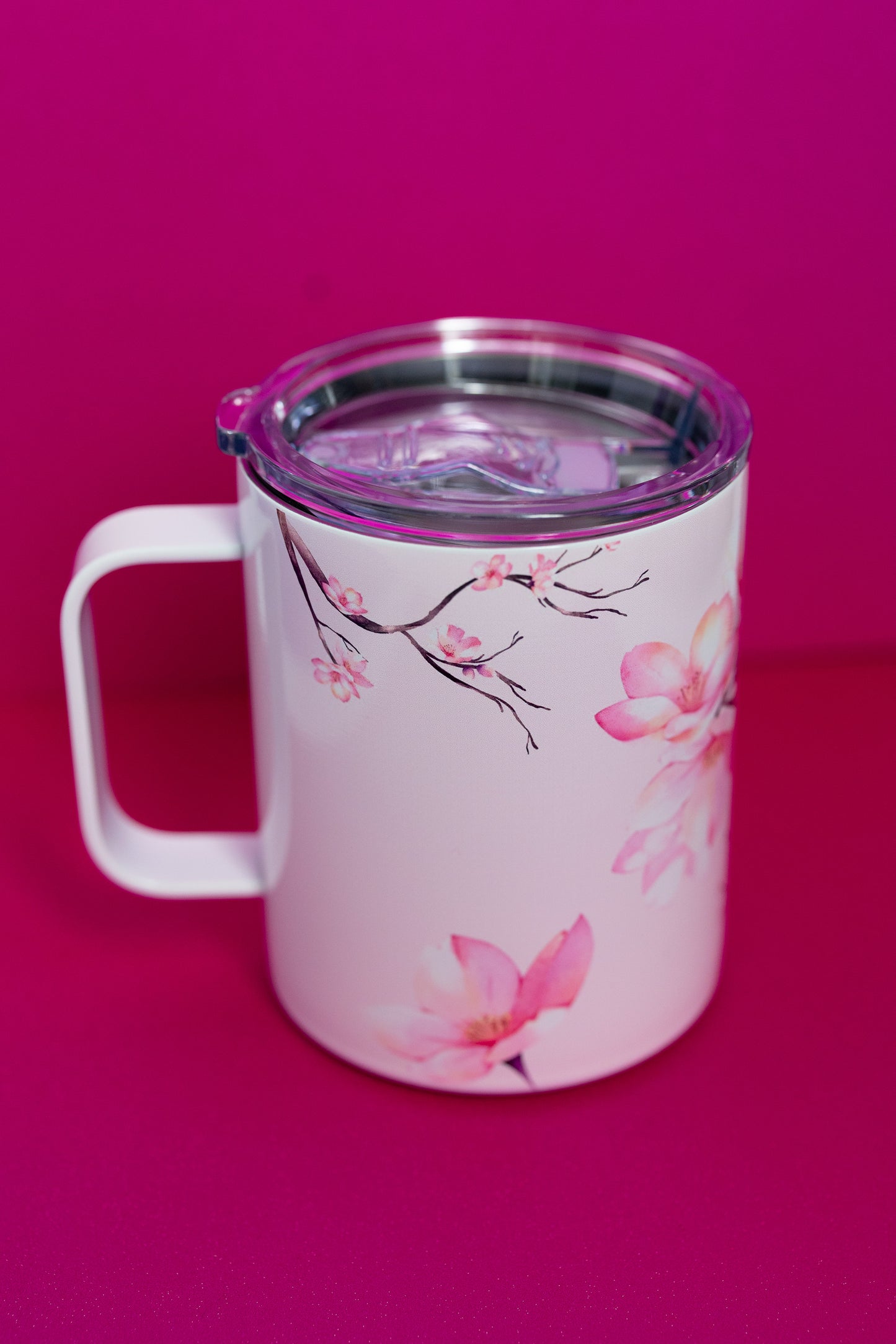 Angled view of Belivra ceramic mug with soft cherry blossom designs on both sides, featuring a spill-resistant lid. The mug showcases the delicate beauty of floral illustrations, perfect for sipping your favorite beverages while embracing mindfulness and creativity. Ideal for daily use, morning rituals, or as an empowering gift for women who appreciate elegance and self-care.