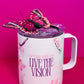 A Belivra ceramic mug featuring the empowering phrase "Sip the Dream, Live the Vision" in purple text, accompanied by delicate cherry blossom designs. The mug is topped with a vibrant butterfly decoration, adding a whimsical touch. Perfect for sipping your favorite beverage while embracing positive affirmations. The mug also features a spill-resistant lid, ideal for those on the go.