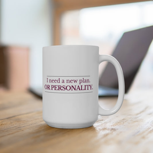 White ceramic mug with “I need a new plan. Or personality.” text on desk with laptop background