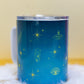 Angled side view of Belivra ceramic mug with mystical blue design featuring celestial symbols like stars, crystals, a moth, and third-eye imagery in vibrant yellow. The mug is displayed with a clear, spill-resistant lid, making it perfect for secure sipping on-the-go. Ideal for spiritual morning routines, tea lovers, and empowered women seeking mindful moments throughout their day.