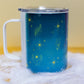 Angled view of Belivra ceramic mug with celestial blue background, featuring glowing yellow symbols like a feather, hands, crystals, and stars. The mug is shown with a spill-resistant clear lid, ideal for enjoying tea, coffee, or other beverages while embracing mindfulness. Perfect for empowered women, spiritual routines, and cozy moments.