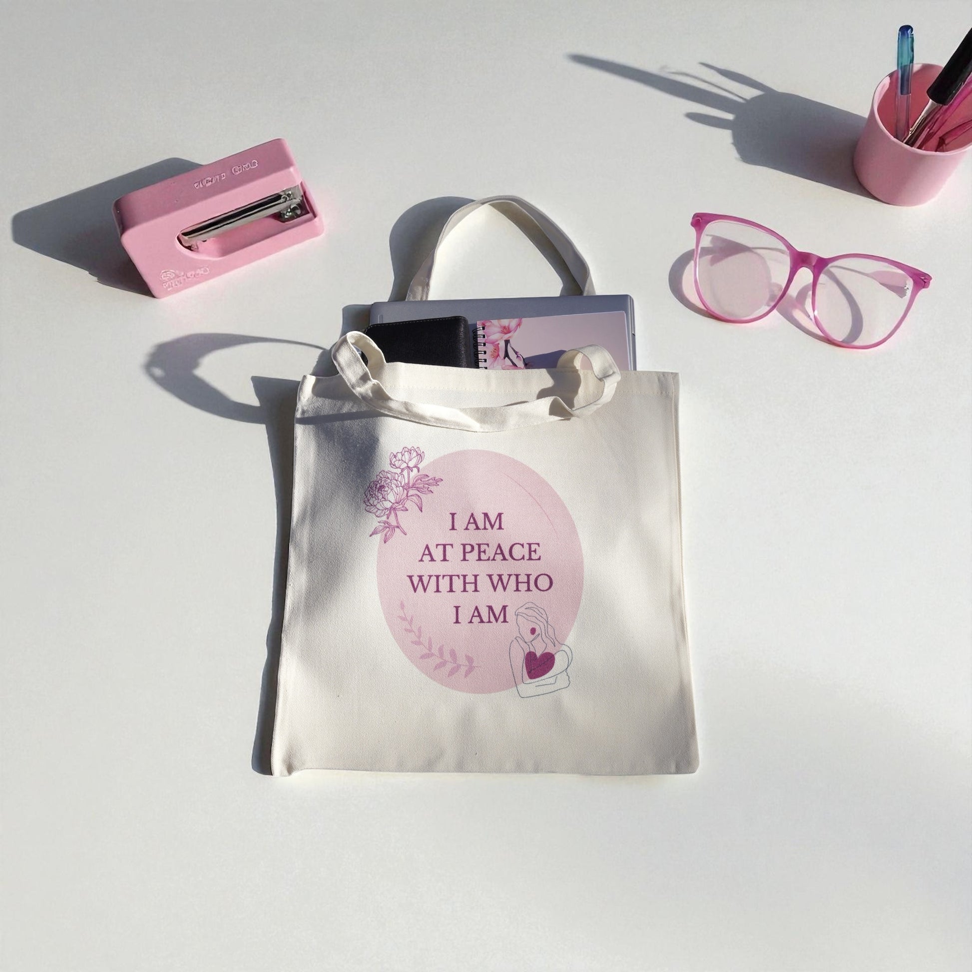 Cream tote bag with the quote “I Am at Peace with Who I Am” in soft plum and blush tones, featuring floral and feminine line art symbolizing mindfulness and self-love.