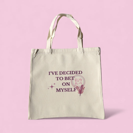 Cream tote bag with the quote “I’ve Decided to Bet on Myself” in plum lettering, featuring a minimalist lioness and botanical design representing courage and self-belief.